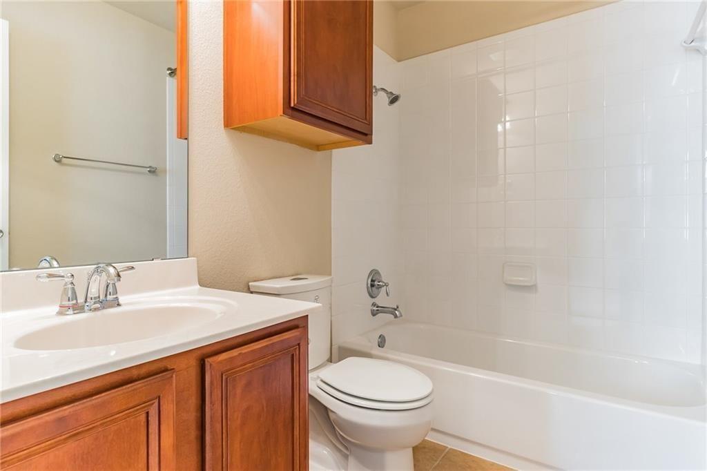 8505 Inca Dove Drive Austin, TX 78729 - Photo 24 of 30 Bathroom featuring a vanity with a white countertop and wood cabinetry, a mirror, and a shower-tub combination with white tiled walls