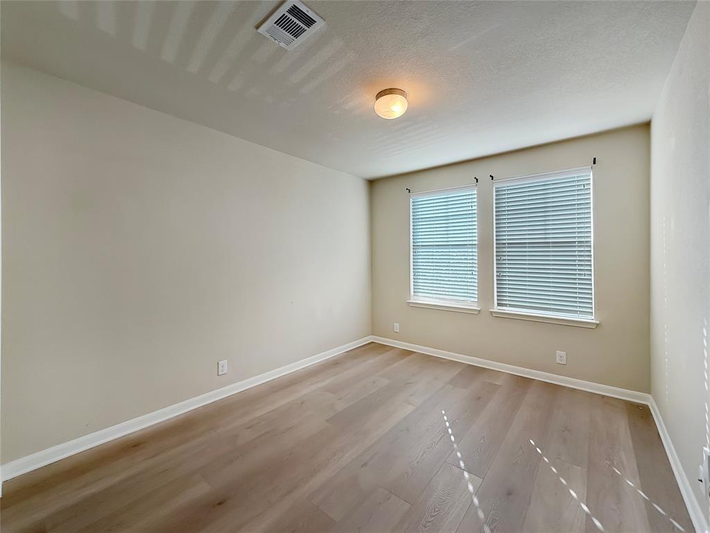 8505 Inca Dove Drive Austin, TX 78729 - Photo 26 of 30 This room features two windows with blinds, light-colored walls, and wood-look flooring