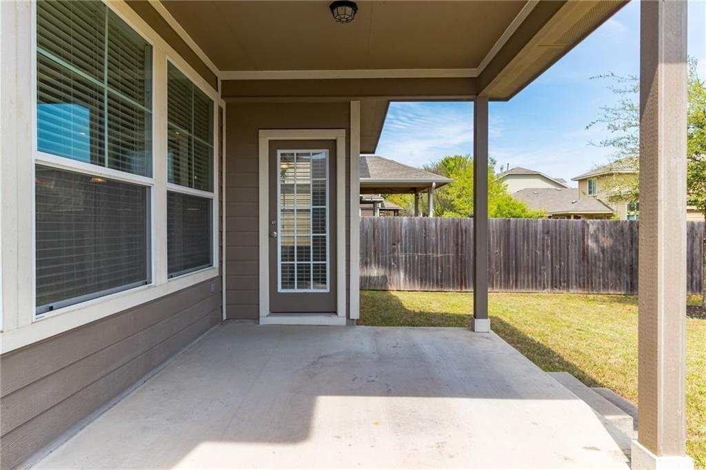 8505 Inca Dove Drive Austin, TX 78729 - Photo 27 of 30 The property features a covered patio with a concrete surface, leading to a yard with a lawn and a wooden fence