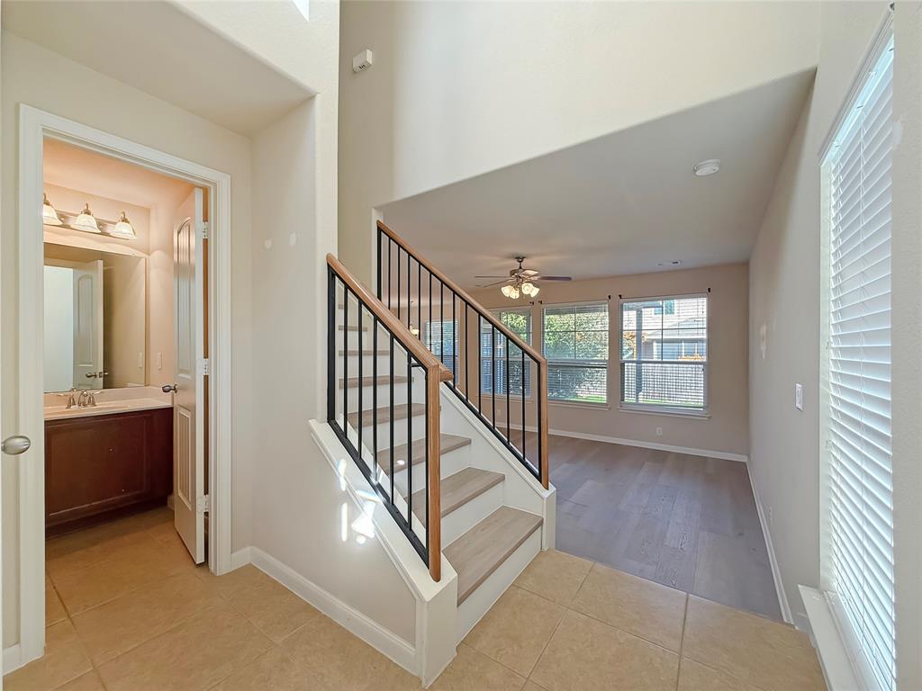 8505 Inca Dove Drive Austin, TX 78729 - Photo 4 of 30 The entryway features tile flooring, leading to a staircase with wood steps and a black metal railing