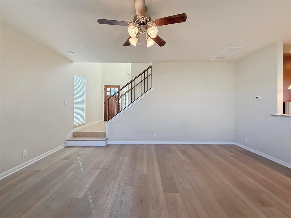 8505 Inca Dove Drive Austin, TX 78729 - Photo 5 of 30 This inviting living area features hardwood floors, a ceiling fan with integrated lighting, and a staircase with a dark metal railing