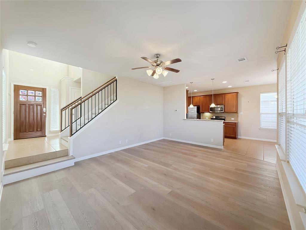 8505 Inca Dove Drive Austin, TX 78729 - Photo 6 of 30 The property features an open-concept living area with light-toned flooring, a ceiling fan, and a kitchen with dark cabinetry, stainless steel appliances, and pendant lighting
