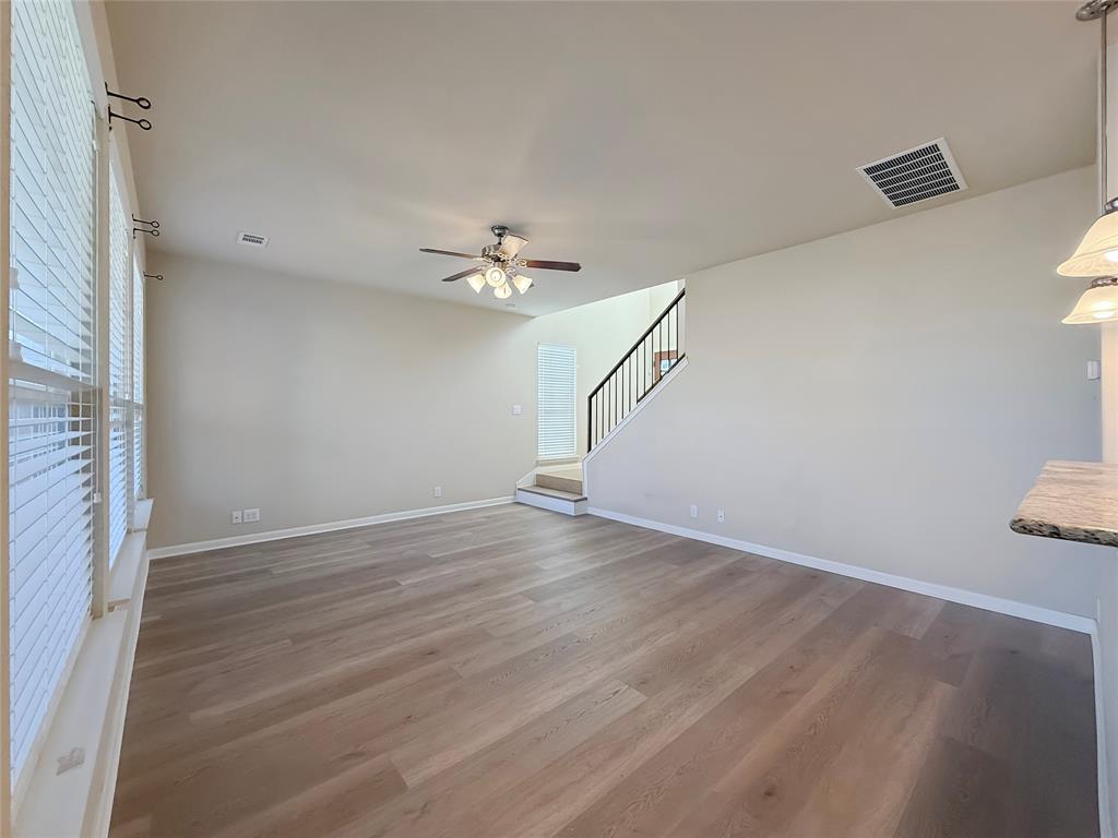 8505 Inca Dove Drive Austin, TX 78729 - Photo 8 of 30 Spacious living area featuring light-toned flooring, windows with blinds, a ceiling fan, and a staircase with a dark railing