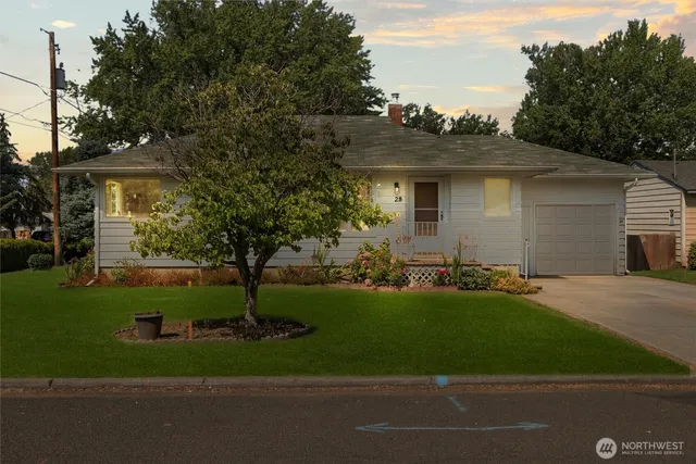 a front view of a house with a garden and trees