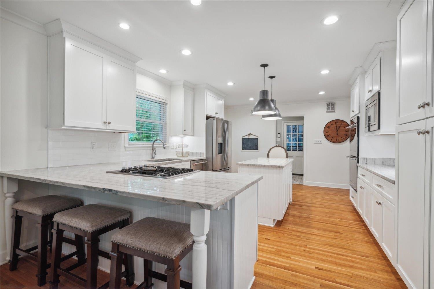 1141 Fair Meadow Road Memphis, TN 38117 - Photo 15 of 40 Kitchen featuring appliances with stainless steel finishes, light hardwood / wood-style flooring, kitchen peninsula, decorative light fixtures, and decorative backsplash
