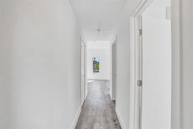 a view of a hallway with wooden floor and a door