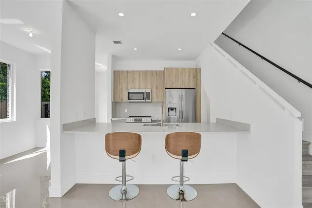 a kitchen with stainless steel appliances granite countertop a sink a stove a refrigerator with a dining table and chairs