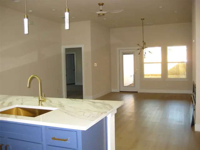 a kitchen with a sink a chandelier and wooden floor
