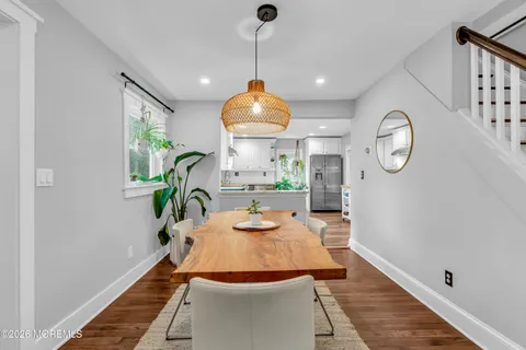 a dining room with wooden floor a chandelier a wooden table and chairs