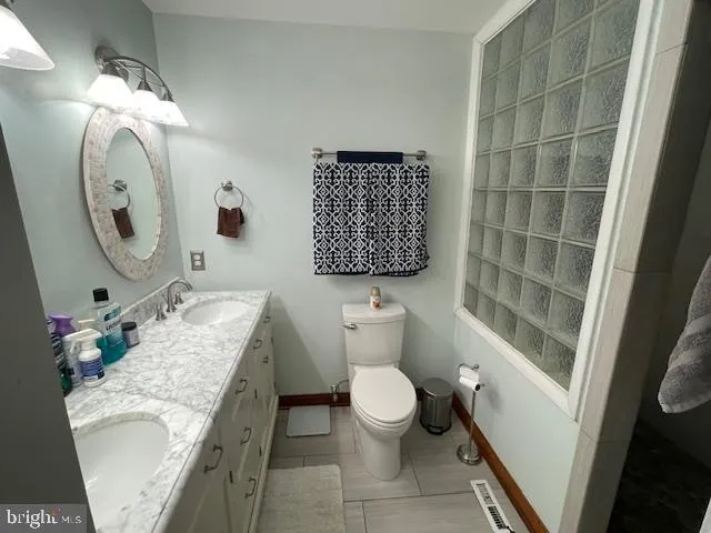 a bathroom with a granite countertop sink mirror vanity and toilet