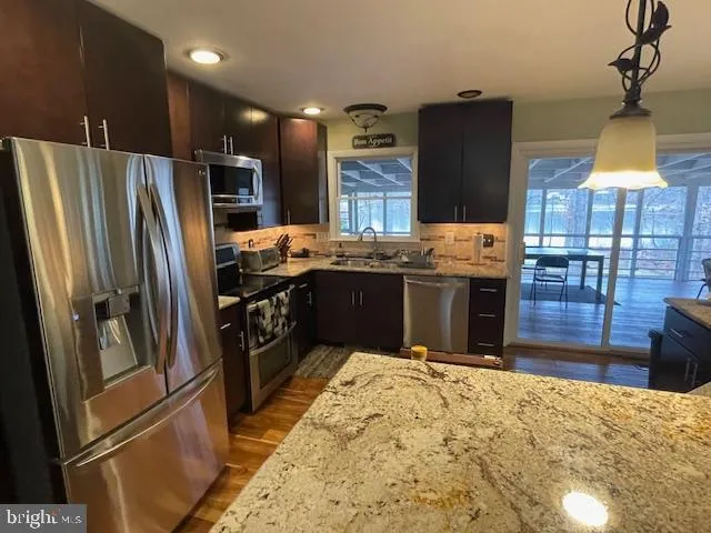 a kitchen with stainless steel appliances granite countertop a refrigerator a stove and a sink