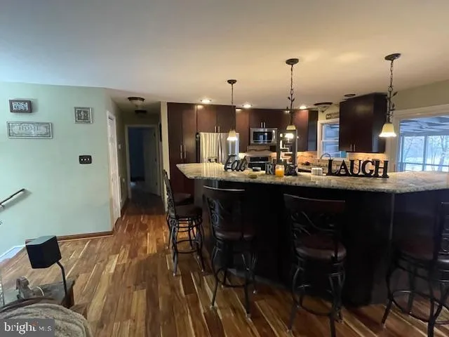 a kitchen with stainless steel appliances kitchen island granite countertop a stove a sink and a wooden cabinets