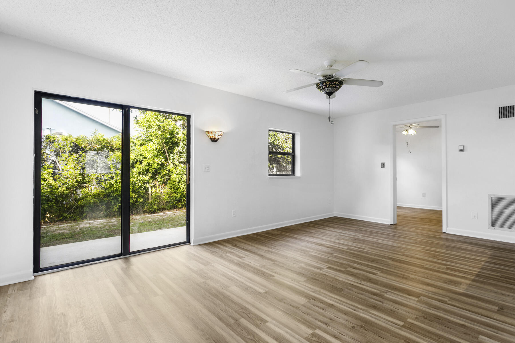 6075 Wolfe Street Jupiter, FL 33458 - Photo 13 of 27 a view of an empty room with a window and wooden floor