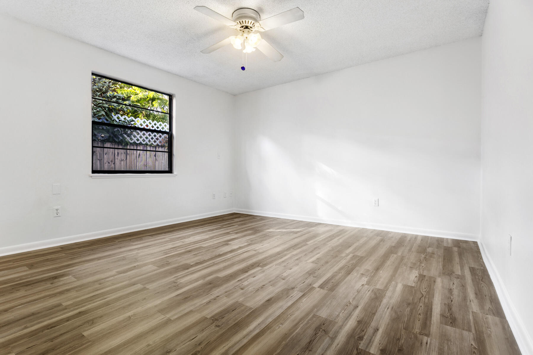 6075 Wolfe Street Jupiter, FL 33458 - Photo 16 of 27 an empty room with wooden floor fan and windows