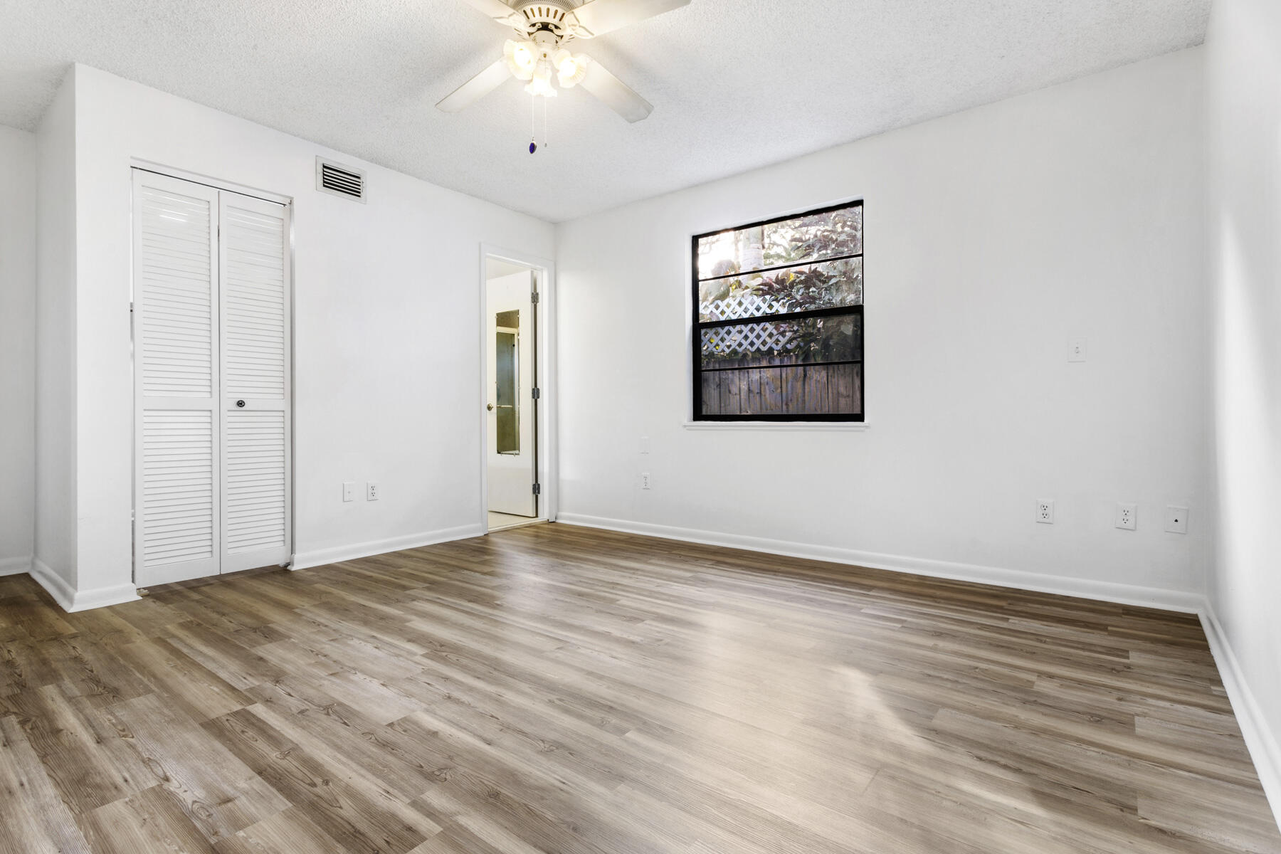 6075 Wolfe Street Jupiter, FL 33458 - Photo 17 of 27 a view of an empty room with wooden floor and a window