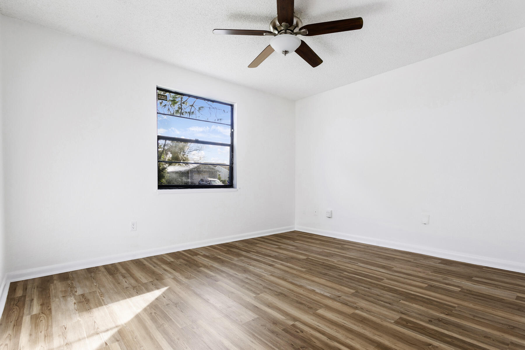 6075 Wolfe Street Jupiter, FL 33458 - Photo 19 of 27 an empty room with a ceiling fan and wooden floor