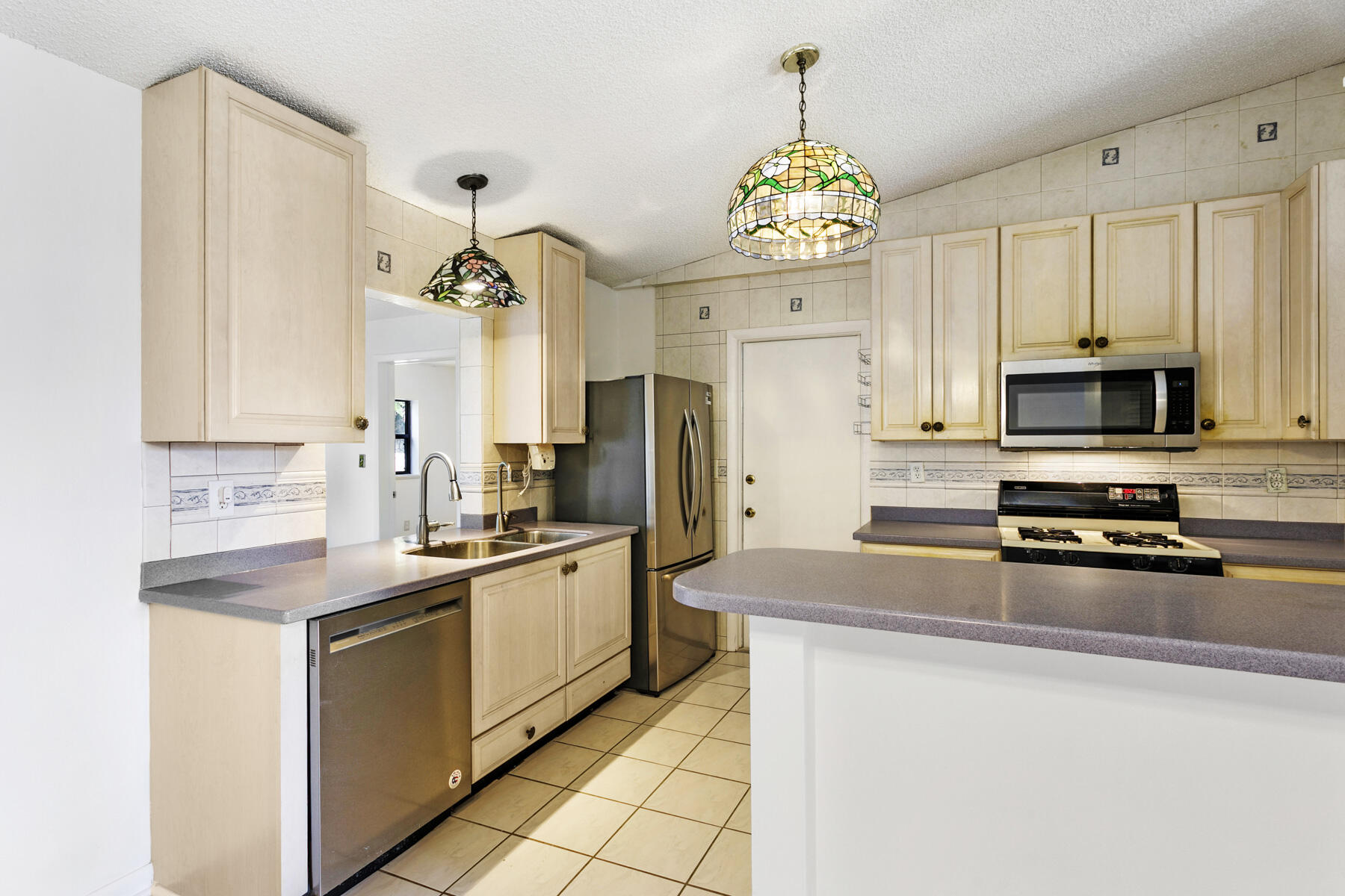 6075 Wolfe Street Jupiter, FL 33458 - Photo 7 of 27 a kitchen with stainless steel appliances a stove refrigerator sink and microwave