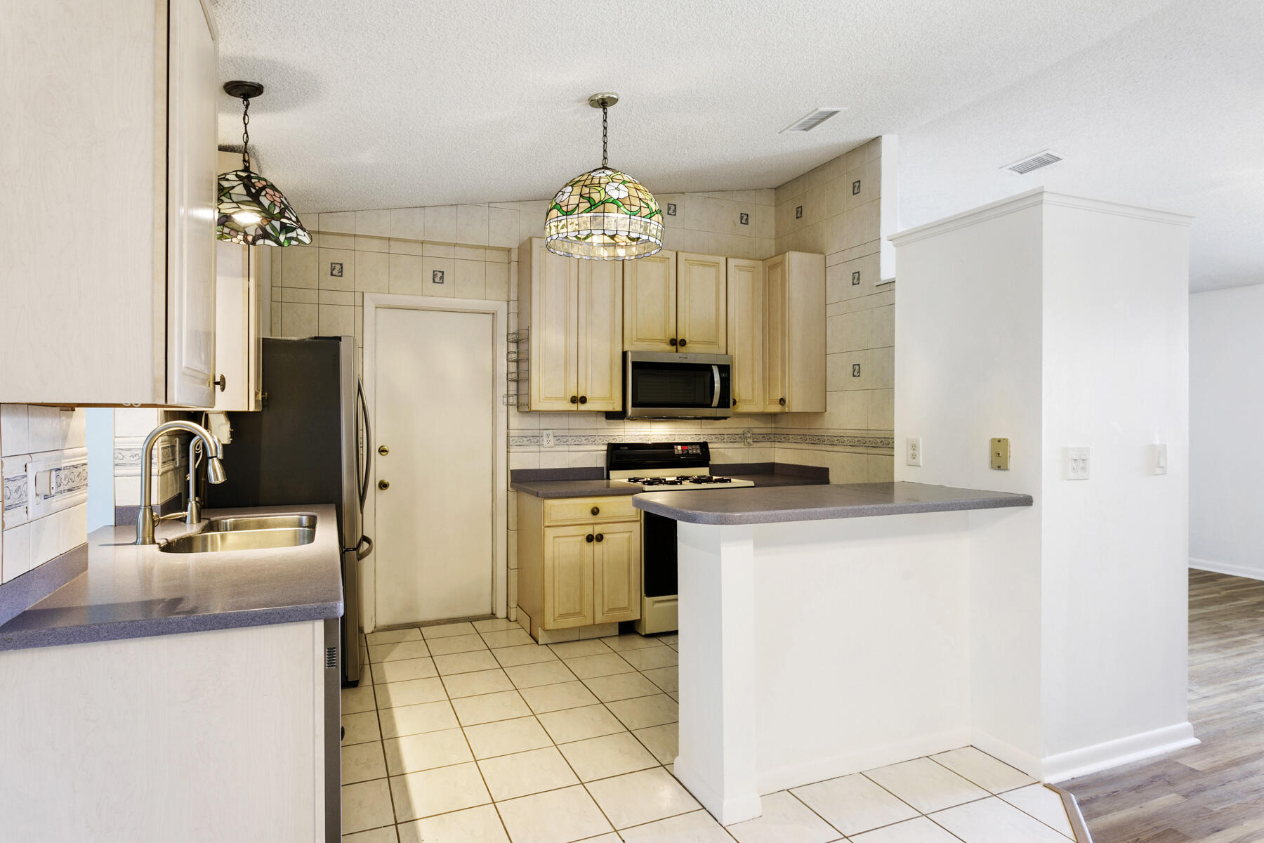6075 Wolfe Street Jupiter, FL 33458 - Photo 8 of 27 a kitchen with refrigerator and microwave
