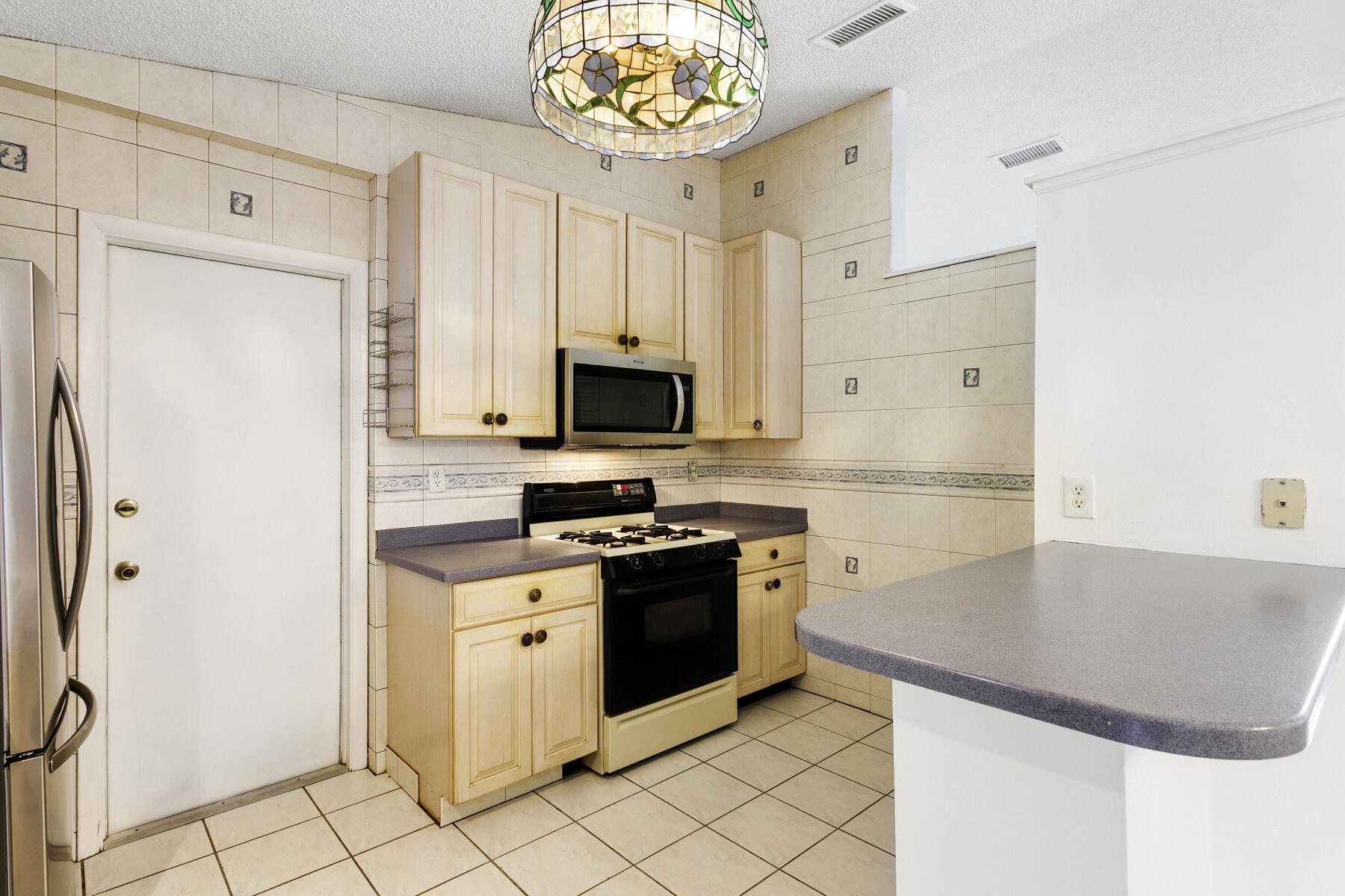 6075 Wolfe Street Jupiter, FL 33458 - Photo 9 of 27 a kitchen with stainless steel appliances granite countertop a refrigerator a stove top oven and a sink
