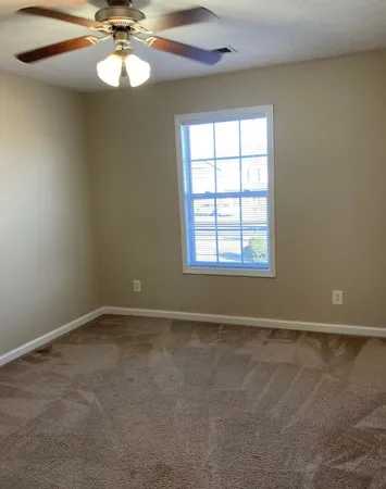 an empty room with a chandelier fan and windows