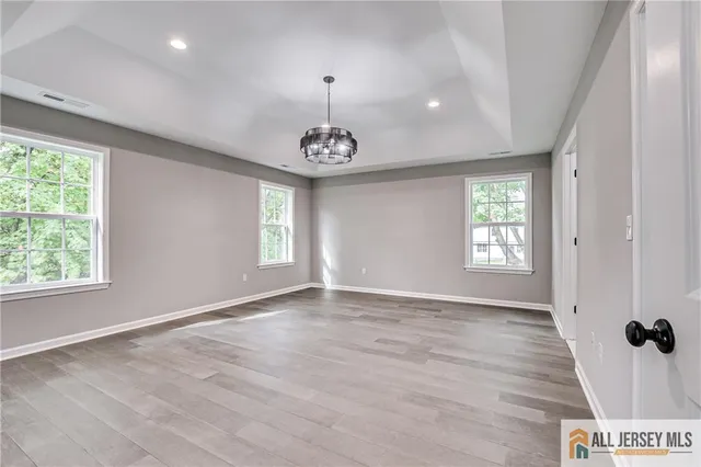 a view of empty room with wooden floor and windows