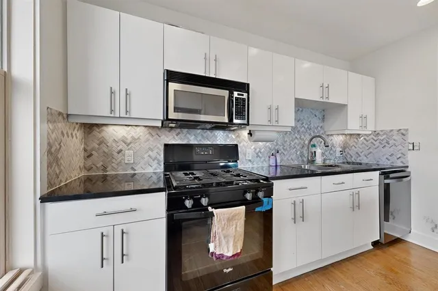 a kitchen with granite countertop white cabinets sink and stainless steel appliances