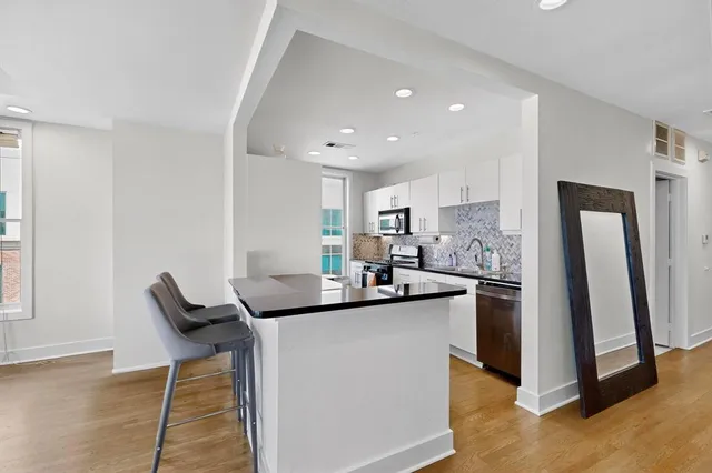 a kitchen with stainless steel appliances kitchen island granite countertop a sink and a refrigerator