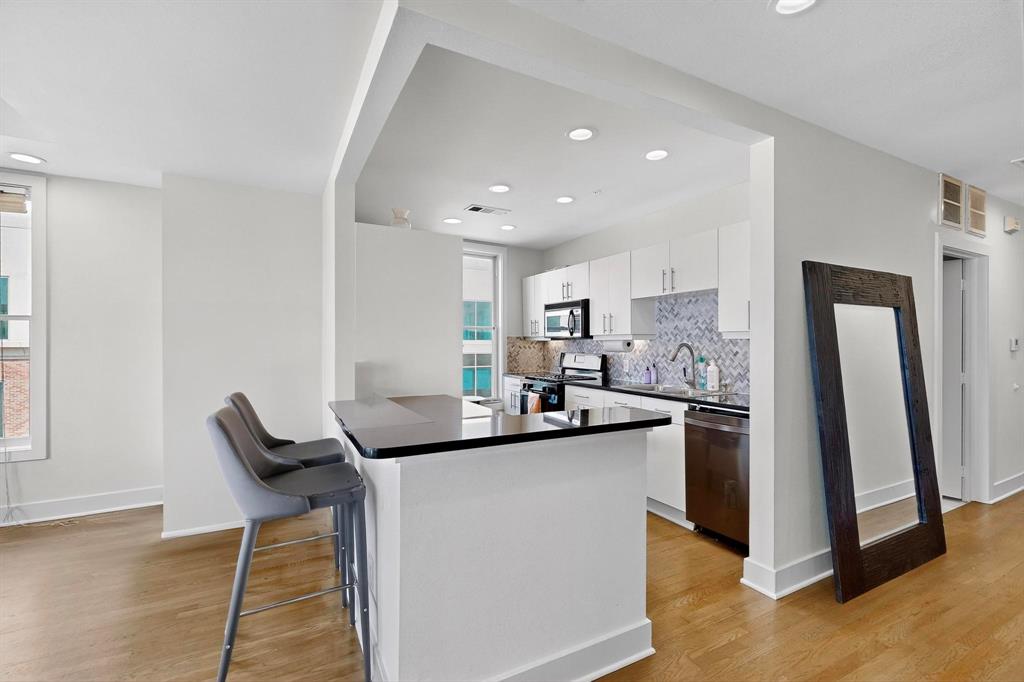 5055 Addison Circle, Unit 736 Addison, TX 75001 - Photo 15 of 34 a kitchen with stainless steel appliances kitchen island granite countertop a sink and a refrigerator