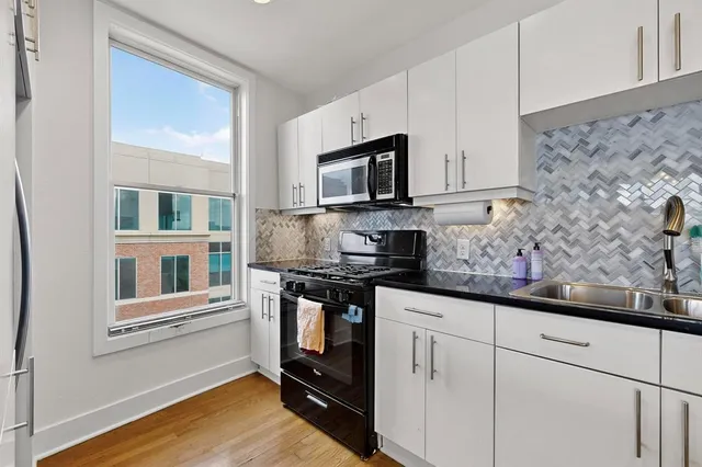 a kitchen with stainless steel appliances granite countertop a stove a sink and a microwave