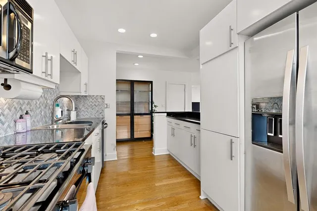 a kitchen with stainless steel appliances granite countertop a refrigerator a stove and a sink