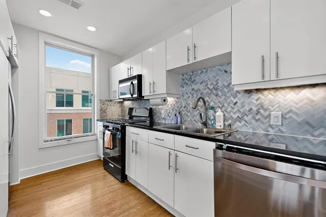 a kitchen with stainless steel appliances granite countertop a sink a stove and a refrigerator