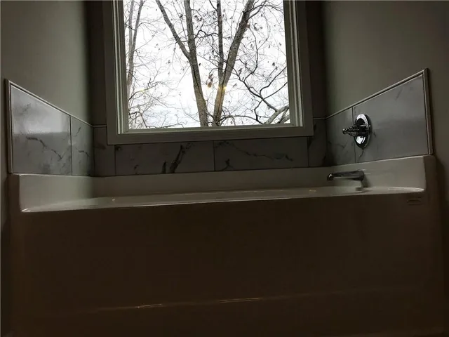 an empty room with wooden floor fireplace and windows