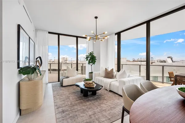 a living room with furniture large windows and a chandelier