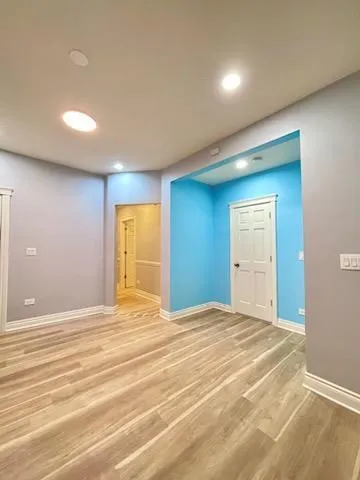 a view of an empty room with wooden floor and closet