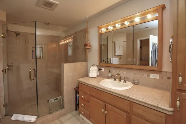 a bathroom with a shower sink vanity granite and mirror