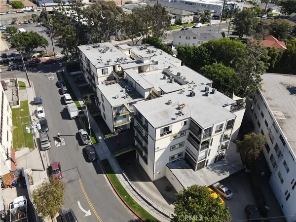 an aerial view of a residential apartment building with a yard and parking spaces