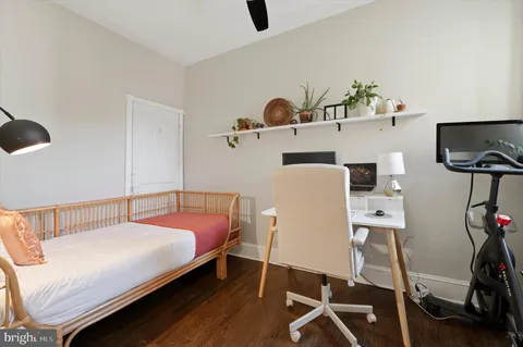 a bedroom with a bed a flat screen tv and gym equipment