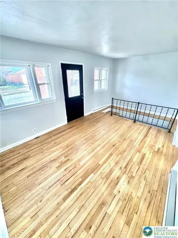 a view of an empty room with wooden floor and windows