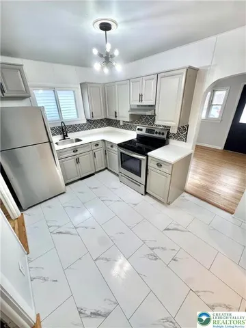 a kitchen with granite countertop a sink a counter top space cabinets and stainless steel appliances