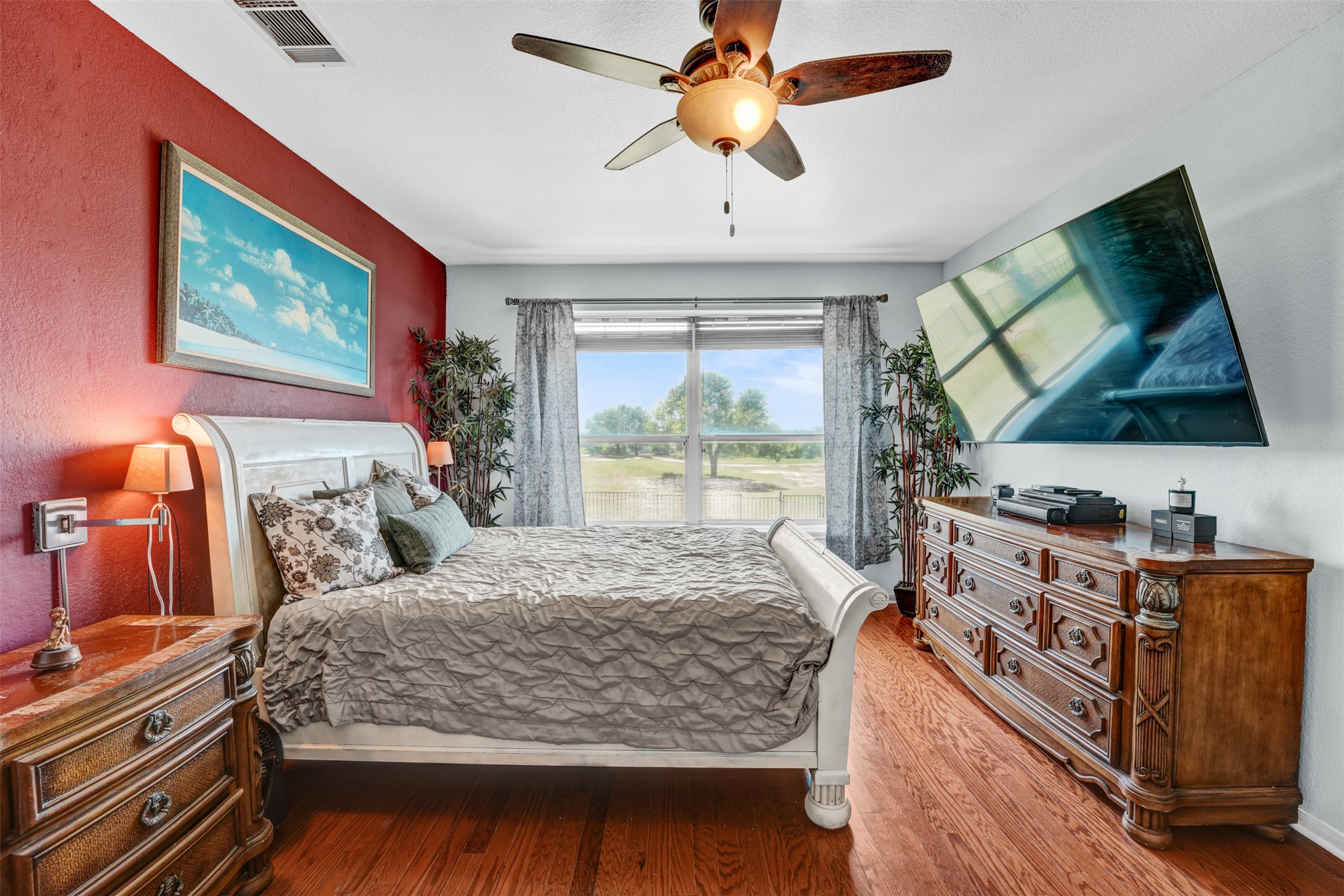 2521 Amen Corner Road Pflugerville, TX 78660 - Photo 19 of 40 Bedroom featuring wood-finish flooring, a ceiling fan with light fixture, and a large window with drapes