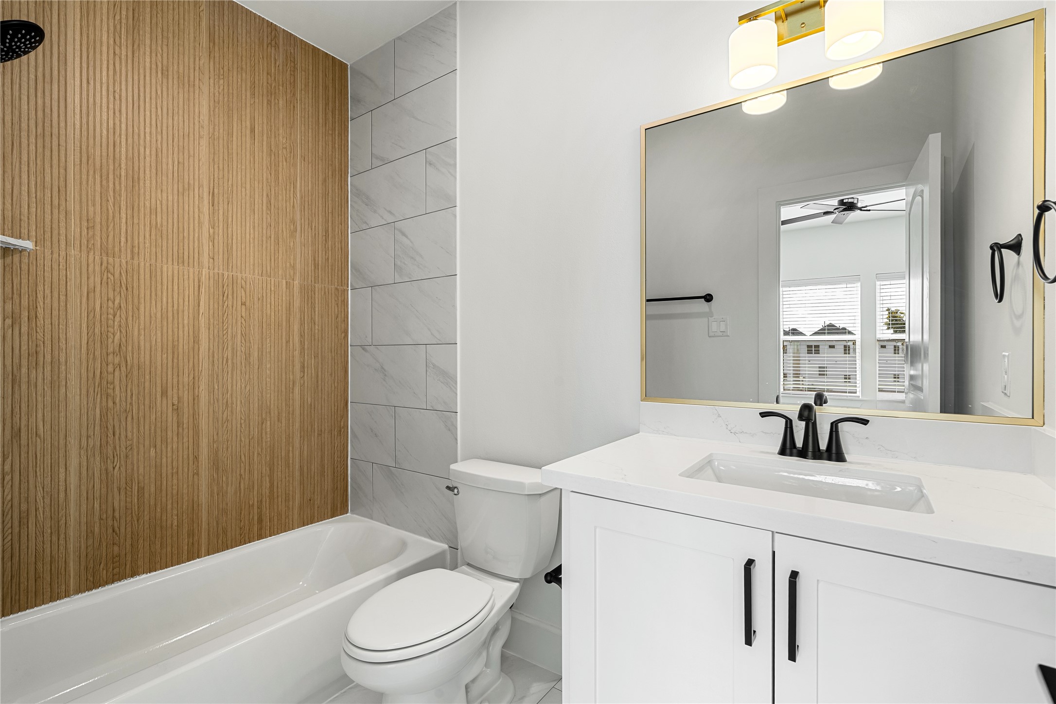 1614 Ojeman Road, Unit E Houston, TX 77055 - Photo 39 of 50 Beautiful en-suite full bathroom located in the third-floor secondary bedroom, featuring modern finishes, a quartz vanity, and a stylish wood-accented shower wall.