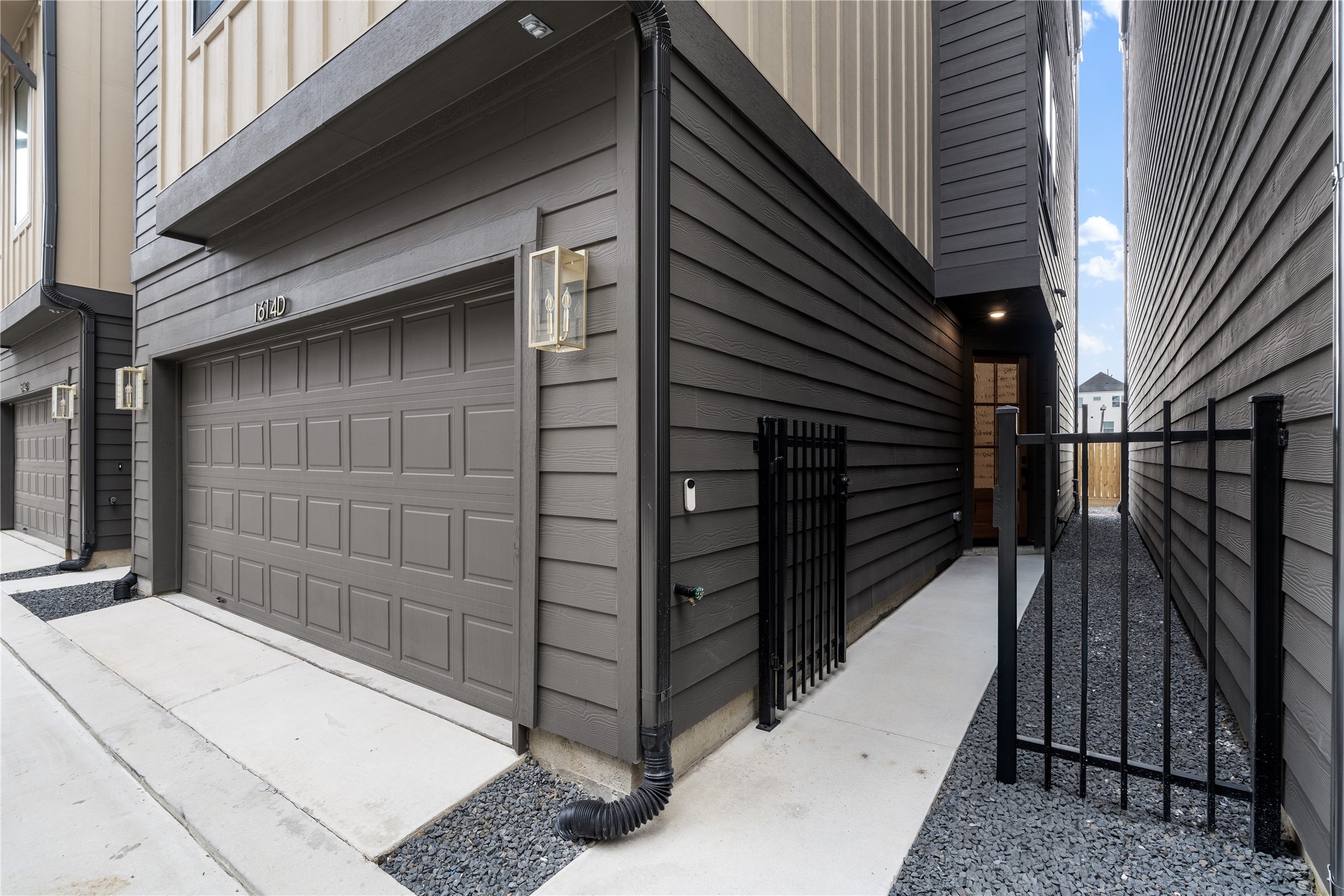 1614 Ojeman Road, Unit E Houston, TX 77055 - Photo 4 of 50 A gated walkway leads to the side entrance, offering both security and privacy. The dark siding and modern light fixtures enhance the sleek design.