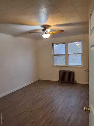 a view of an empty room with a window and wooden floor