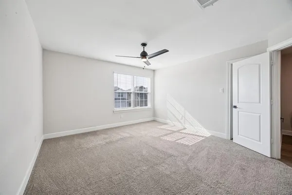 an empty room with windows and ceiling fan