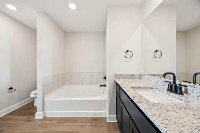 a bathroom with a granite countertop sink and mirror with bathtub