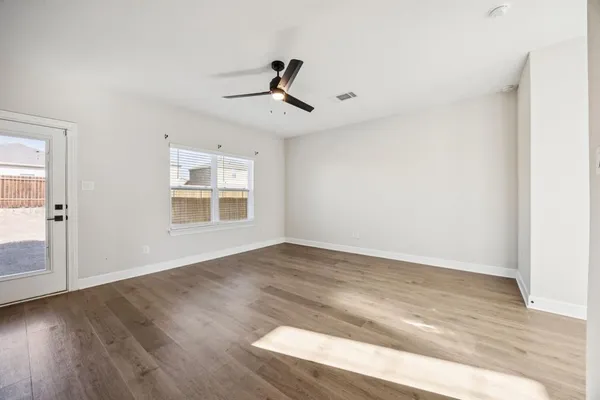 an empty room with wooden floor cabinet and windows