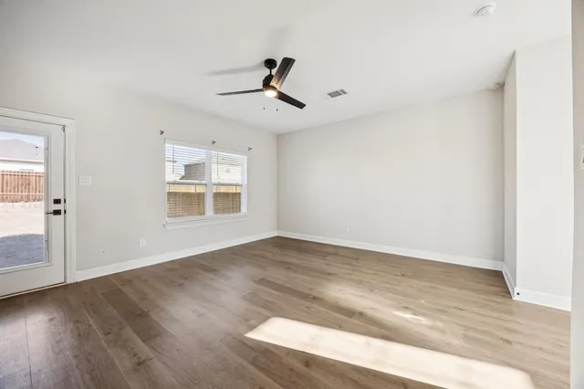 an empty room with wooden floor cabinet and windows