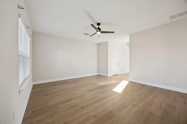 a view of an empty room with wooden floor and a window