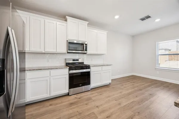 a kitchen with granite countertop white cabinets and stainless steel appliances