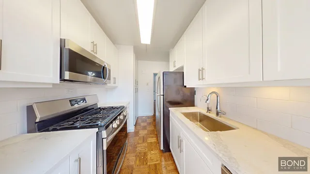 a kitchen with stainless steel appliances granite countertop a sink a stove a refrigerator a microwave oven with white cabinets